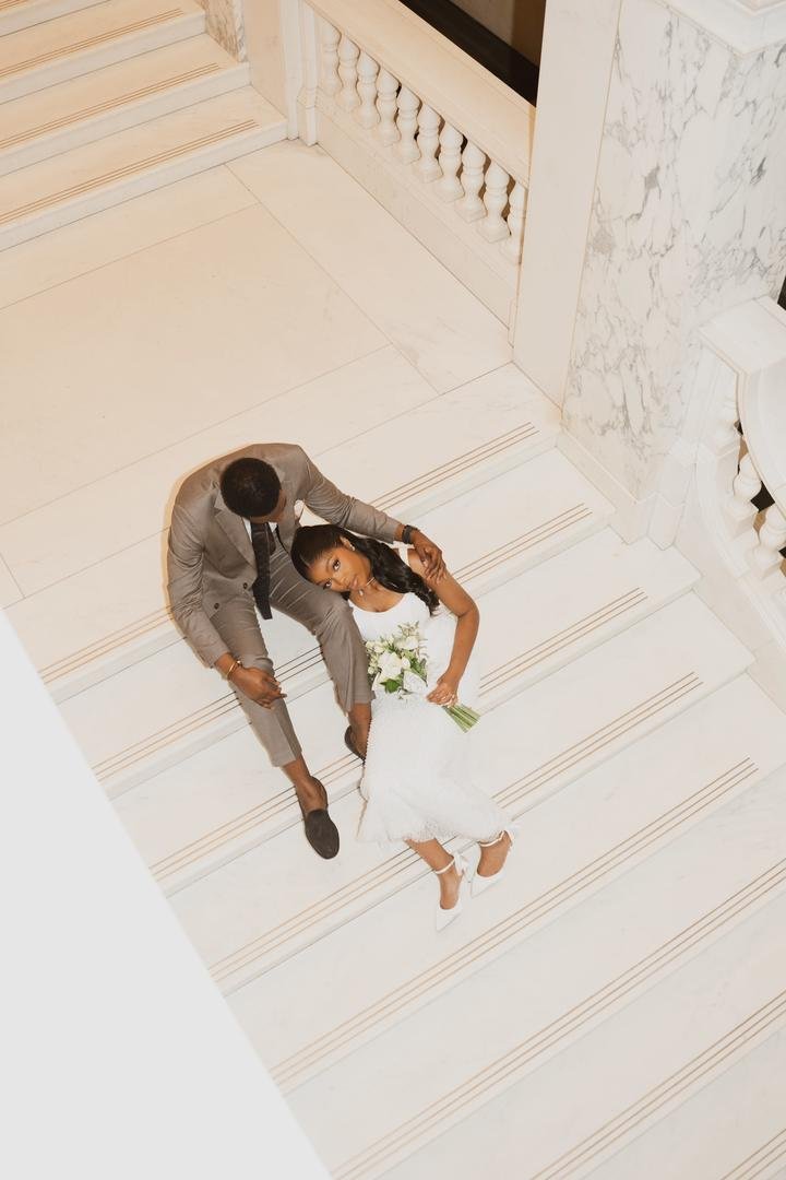 Bride and groom seated together on a marble staircase